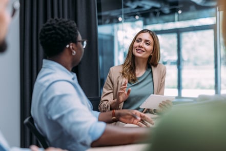 two workers in light conversation at desk