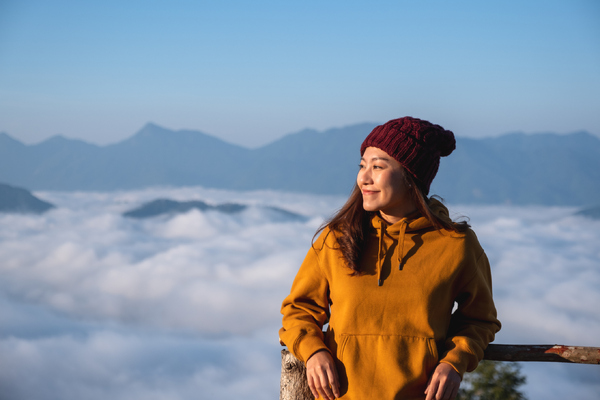 hiker in hat smiling above cloud cover