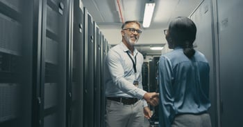 man and woman shaking hands in a datacenter with server racks