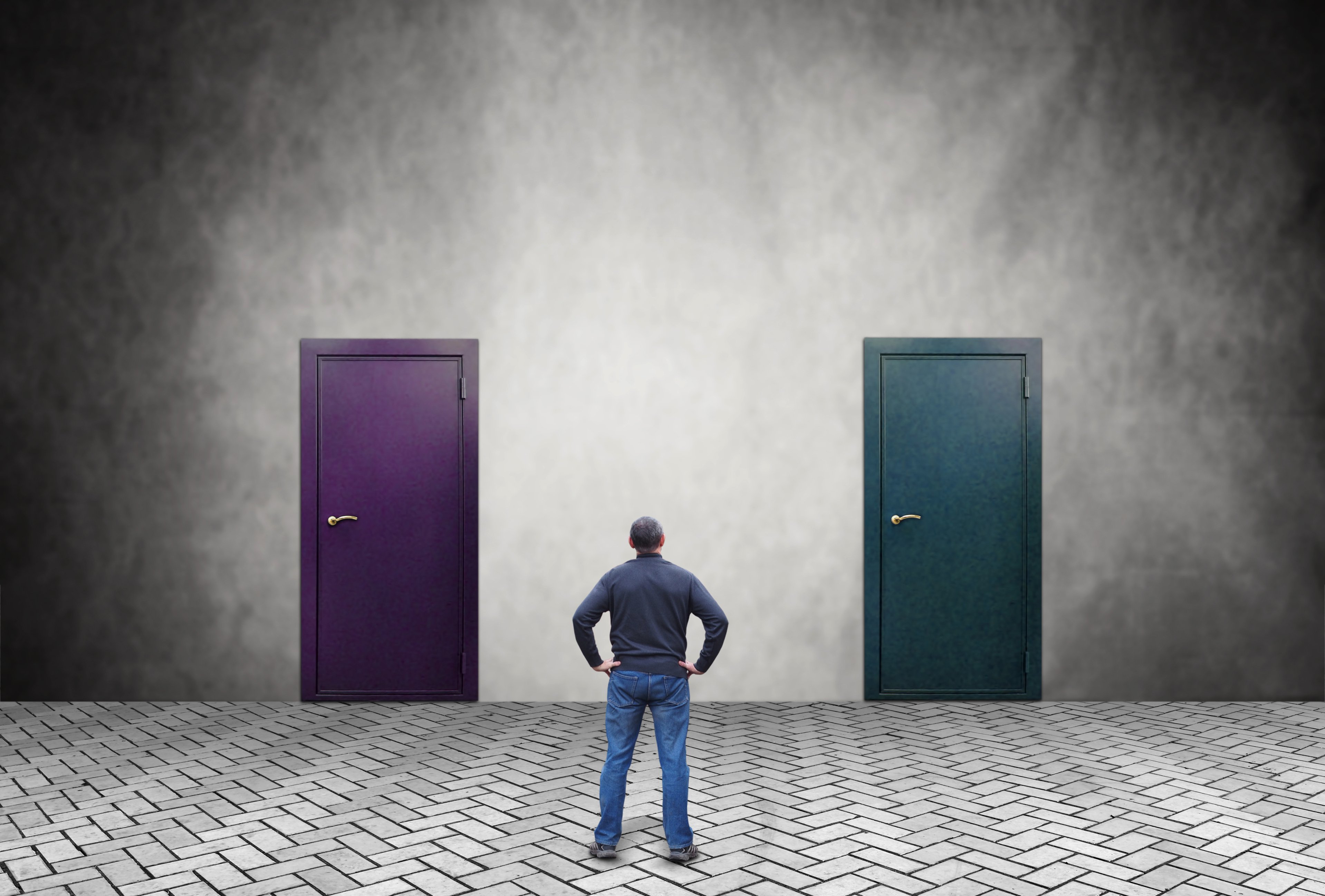 man standing in front of two doors trying to decide on one