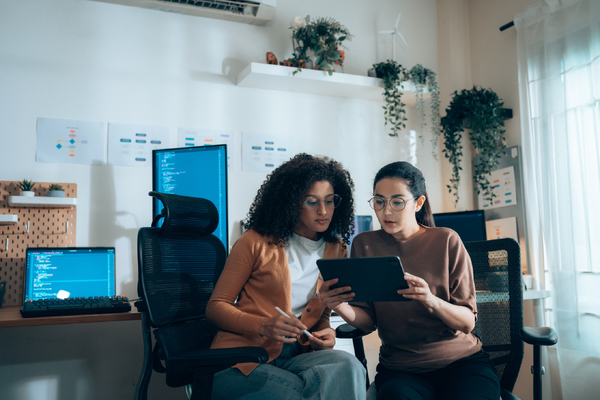two women looking at tablet and having a discussion in offic