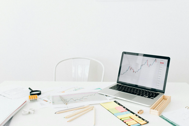 Charts and Colored Pencils on a Desk Next to a Laptop